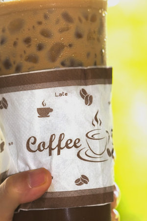 Hand and ice coffee of cup with font selective focusの写真素材
