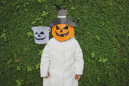 Poor kids play Halloween with the mask handmade on green grassの写真素材