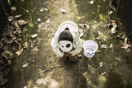Poor kids play Halloween with the mask handmade alone dark toneの写真素材