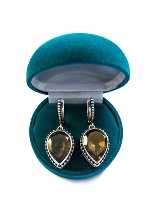 Silver earrings with big topaz in a box isolated over whiteの写真素材