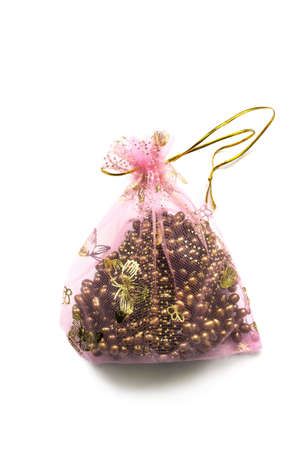 Yellow pearl in a pink transparent bag isolated over whiteの写真素材