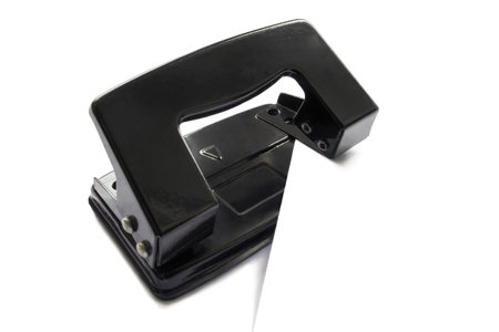 Black puncher with sheet of paper isolated over whiteの写真素材