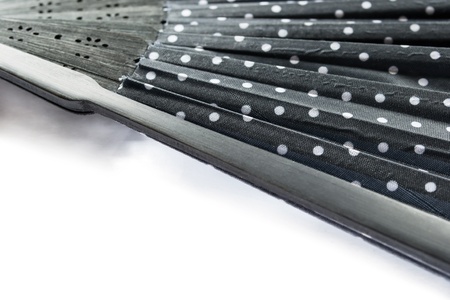 Part of opened black textile fan on a wooden frame on white backgroundの写真素材