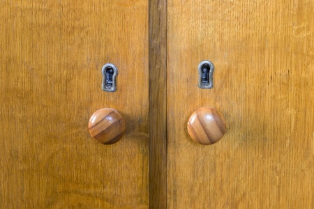 Two old wooden doors with round handles and keyholes closeupの写真素材