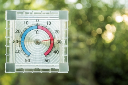 Twenty seven degrees above zero on the thermometer over green foliage blur backgroundの写真素材