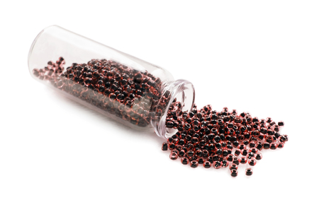 Red glass beads sprinkled out of glass jar isolated over whiteの写真素材