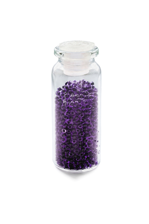 Bright violet beads in a glass vial isolated over whiteの写真素材