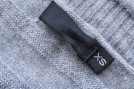 Black label with XS size on gray knitted sweaterの写真素材
