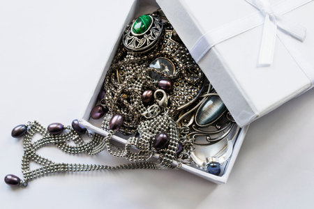 Different jewels with pearl and gems in white opened box as a background