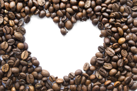 Brown coffee beans with white silhouette f a heart as a backgroundの写真素材