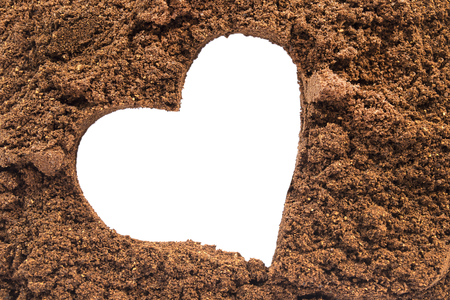 Isolated white silhouette of a heart in brown ground coffee as a backgroundの写真素材