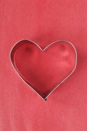 Metallic heart on red paper as a backgroundの写真素材