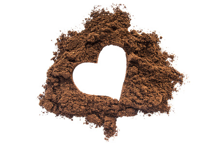Spilled ground coffee with a print of a heart isolated over whiteの写真素材