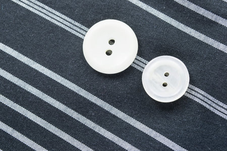 Pair of white buttons on striped gray cloth as a backgroundの写真素材