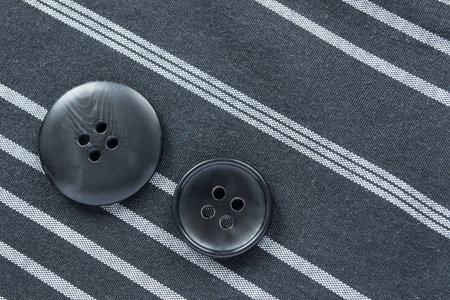 Pair of black buttons on striped fabrics as a background