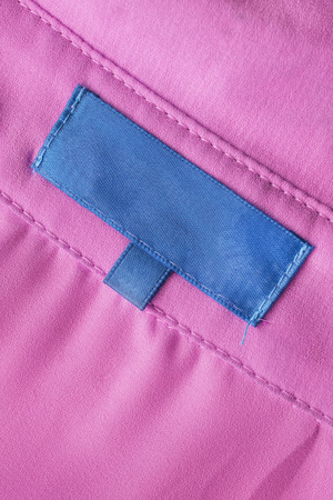 Blank blue label on pink cloth closeup as a backgroundの写真素材