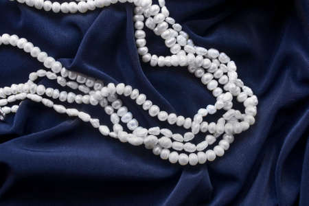 Strings of white pearl on dark blue silk as a backgroundの写真素材