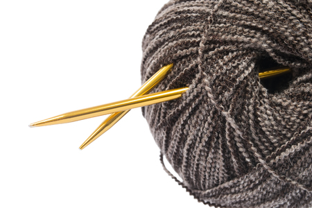 Golden knitting needles in a ball of melange yarn closeup over whiteの写真素材