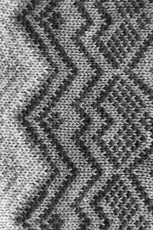 Gray knitting with black ornament closeup as a backgroundの写真素材