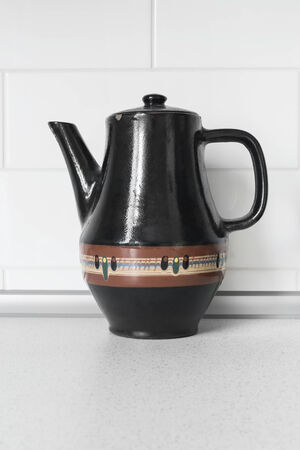 Black ceramic pot standing against white wallの写真素材