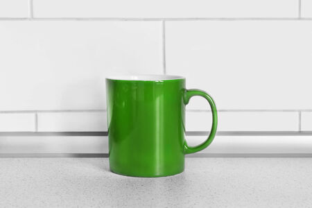Green mug on a table against brick wall as a backgroundの写真素材