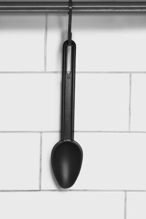 Plastic black spoon hanging against brick wall as a backgroundの写真素材