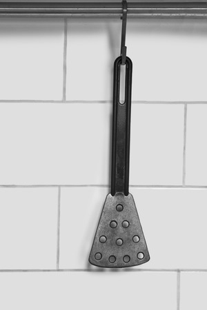 Black cooking spatula hanging against the wall as a backgroundの写真素材