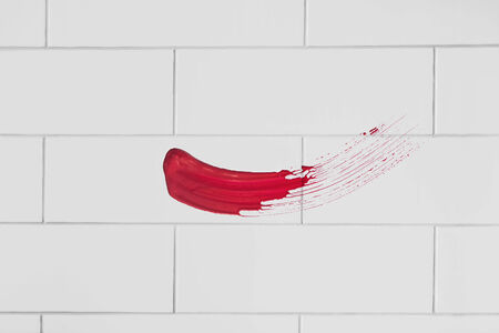 Red paint brush stroke over blank wall as a backgroundの写真素材
