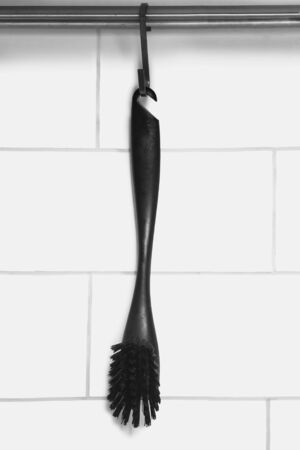 Black brush hanging against white brick wallの写真素材