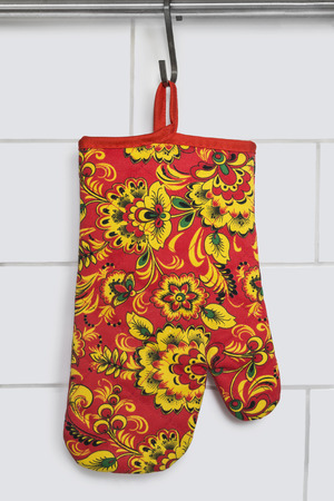 Red ornamental oven-glove hanging over brick wall as a backgroundの写真素材