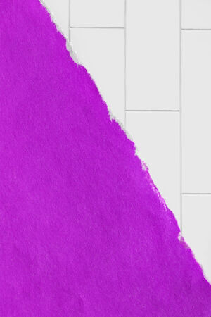 Torn purple paper over white brick wall as a backgroundの写真素材