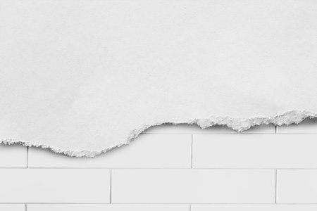 Torn white  paper over white brick wall as a backgroundの写真素材