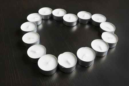 Tea light in the shape of a heart on dark wooden floorの写真素材