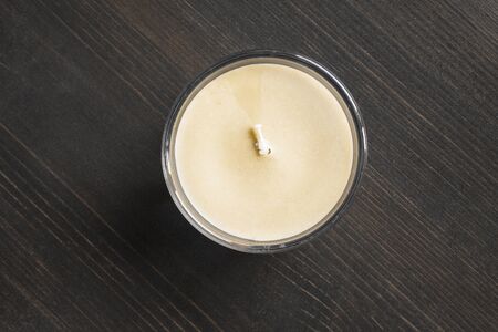 Candle standing on dark wooden desk as a backgroundの写真素材