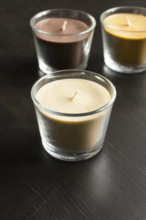 Group of aromatic candles in glass candlesticks on dark wooden deskの写真素材
