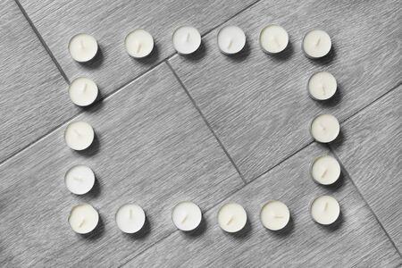 Frame of tea lights on gray wooden floor as a backgroundの写真素材