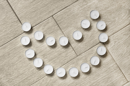 White tea lights in the shape of a crescent on wooden floorの写真素材