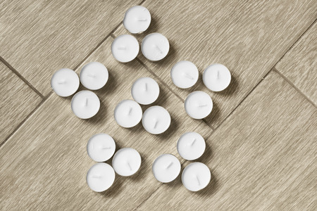 White tea lights in the shape of a star on wooden floorの写真素材