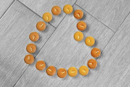 Yellow candles in the shape of a heart on wooden backgroundの写真素材