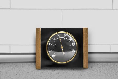 Vintage indoor thermometer standing on a table against white brick wallの写真素材