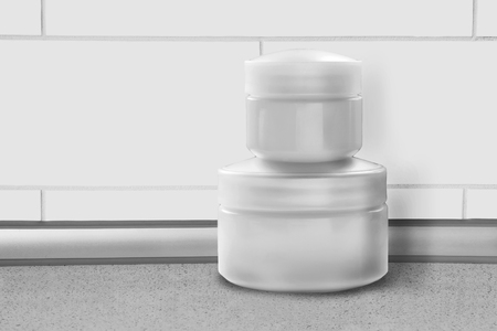 Blank cosmetic jars against white brick wall as a backgroundの写真素材