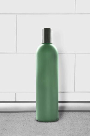 Green blank bottle against white brick wall as a backgroundの写真素材