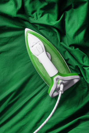 Iron smoothing green cotton cloth as a backgroundの写真素材