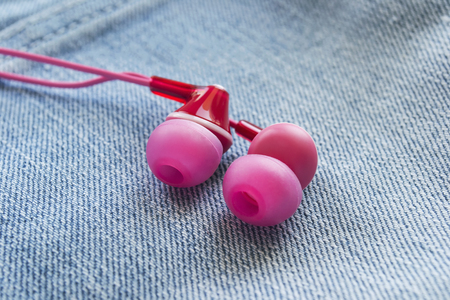 Pink earphones on denim cloth as a backgroundの写真素材
