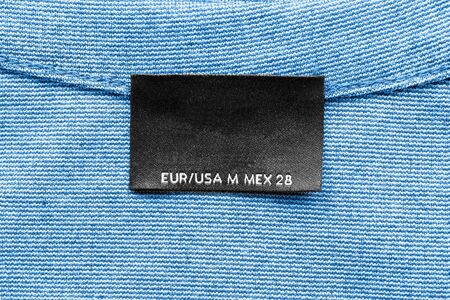 Blank clothes label on blue cloth as a backgroundの写真素材