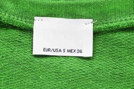 Blank clothes label on green material as a backgroundの写真素材