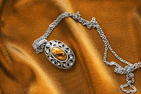 Amber pendant on golden satin as a backgroundの写真素材