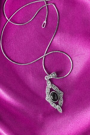 Black onyx pendant on magenta pink satinの写真素材