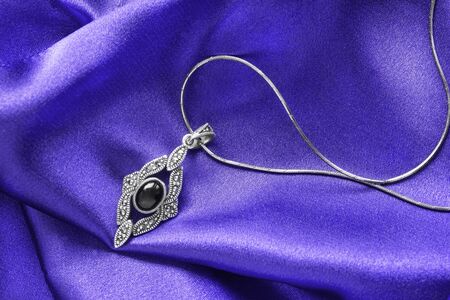 Obsidian silver pendant on purple draped satinの写真素材