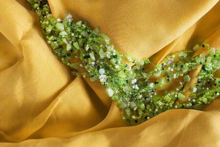 Green beads on golden silk as a backgroundの写真素材